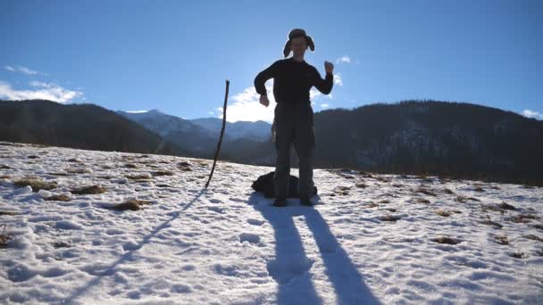 Jovem homem feliz dança engraçado nas montanhas de inverno. Guy dança contra o fundo da paisagem nevada. Turista masculino se divertindo na natureza invernal. Lento movimento Fechar — Vídeo de Stock