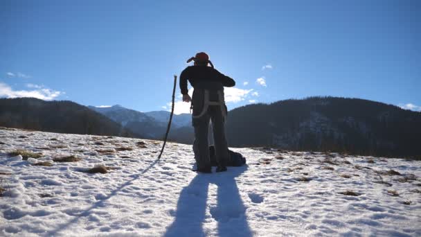 冬の山で認識できない若い男踊り面白い。雪の風景の背景に男踊り。男性の観光客が冬の自然を楽しんでいます。スローモーションのすぐ後方を背面図 — ストック動画