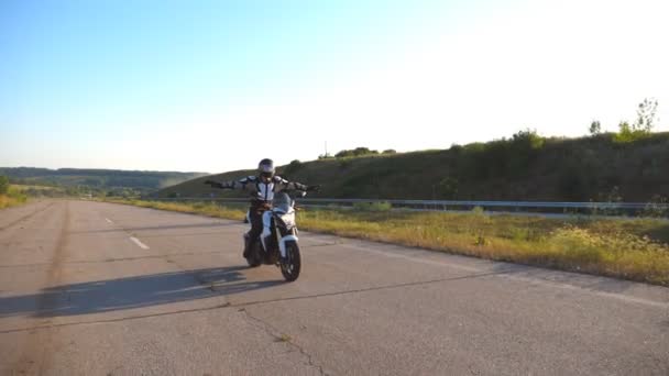 Jovem homem despreocupado andando em uma moto sem mãos. Motociclista dirigindo sua motocicleta na estrada e solte o volante e abra os braços. Conceito de liberdade e segurança. Movimento lento — Vídeo de Stock