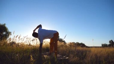 Pratik Yoga mat çayır, sportif adam. Genç alan eğitim güneşli bir adam. Arka plan yaz manzaraya. Sağlıklı aktif yaşam tarzı kavramı. Düşük açılı görünüş
