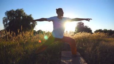 Yakın yukarı pratik yoga genç birini taşır ve mat Field'da konumlandırır. Çayır, streç egzersiz yapan sportif erkek. Arka plan, güzel manzara. Sağlıklı aktif yaşam tarzı kavramı