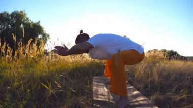 Genç adam pratik Yoga hamle ve mat çayır, konumlandırır. Alan güneşli bir günde eğitim sportif adam. Arka plan yaz manzaraya. Sağlıklı aktif yaşam tarzı. Yan görünümü kapatın