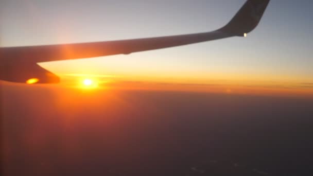 Utsikt från flygplansfönstret till vacker soluppgång eller solnedgång. Flygel och moln på himlen. Resekoncept. Närbild — Stockvideo