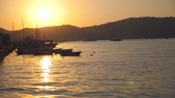 Silhuetas de barcos de pesca em pé perto da praia ao pôr do sol. Navios de pescadores balançando em ondas em bela noite. Fundo da natureza. Bela paisagem. Movimento lento — Vídeo de Stock