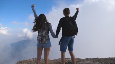 Güzel Kanyon kenarında duran, zaferle yukarı silah outstretching kadın ve erkek. Turist dağ ve yükseltilmiş elleri yukarı ulaşan sırt çantaları ile genç bir çift. Arkadan görünüş ağır çekim