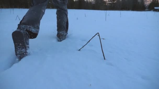 Bakre bakifrån av oigenkännlig kille jogging genom snötäckta gräsmattan vid kanten av skogen. Ung man som kör på snö fältet på kvällen och njuter frihet under vintern reser. Närbild av Slow motion — Stockvideo