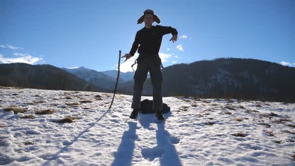 Jovem homem feliz dança engraçado nas montanhas de inverno. Guy dança contra o fundo da paisagem nevada. Turista masculino se divertindo na natureza invernal. Lento movimento Fechar — Vídeo de Stock