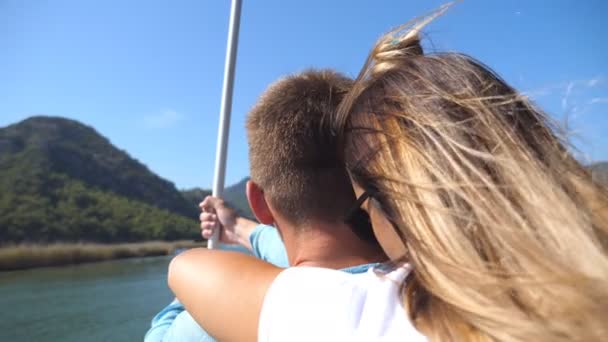 Vista posteriore posteriore della giovane coppia trascorrere del tempo insieme sul ponte di barca a vela nella giornata di sole. Bella ragazza che abbraccia il suo ragazzo da dietro in barca durante il viaggio. Concetto vacanza o vacanza. Da vicino. — Video Stock