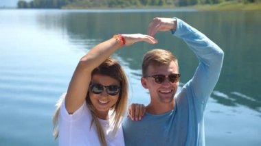 Tekne yay üzerinde oturan ve güneşli günde kameraya poz genç çifti. Gemi güvertesinde birlikte vakit ve yaz zevk aşk mutlu çift seyahat. Tatil veya tatil kavramı. Yakın çekim