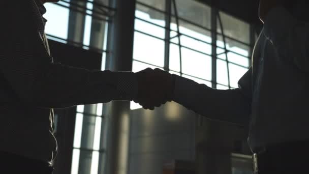 Business handshake indoor at office with sun flare at background. Two businessmen greeting each other. Shaking of male arms intside. Colleagues meet and shake hands. Close up Slow motion — Stock Video