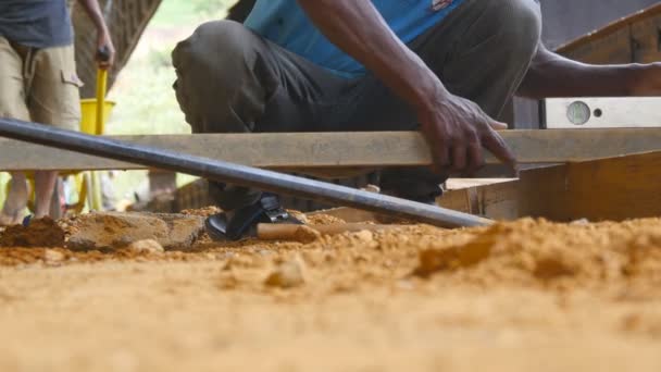 Низкий угол зрения неузнаваемых индейских мужских рук, проверяющих уровень точности при строительстве деревянного пола. Местные строители работают на строительной площадке. Концепция будущего проекта. Закрыть — стоковое видео