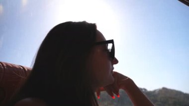 Yaz otobüsle seyahat ve pencereye arıyorum genç kadın. Yolculuk sırasında camdan izlerken güneş gözlüklü kız. Kadın turist autobus arabayla alır. Tatil veya gezi kavramı. Yakın çekim