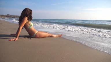 Genç kız deniz sahilde yalan söylemekten ve güneşlenme bikini. Yaz tatil seyahat sırasında deniz kıyısında tanınmaz halde kadın rahatlatıcı. Okyanus dalgaları üzerinden yıkama kadın cesedi bronzlaşmış. Ağır çekim yakın çekim