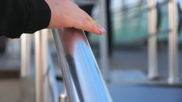 Mano de empresaria deslizándose sobre pasamanos metálicos. Mujer joven irreconocible subiendo escaleras en la oficina moderna o centro comercial. Fondo borroso. Vista detallada Cámara lenta Primer plano — Vídeos de Stock