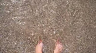 Dişilerin ince ayaklarını okyanus dalgaları kaplıyor. Deniz kıyısında çakıl taşıyla duran ve temiz deniz suyunun gelgitlerinin tadını çıkaran bir kadın. Genç kız deniz kenarında yaz tatilinin tadını çıkarıyor. Trip konsepti. Yavaş çekim POV
