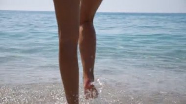 Tazelenmek ya da yüzmek için denize giden seksi genç bir kadın. Pembe bikinili çekici bir kız egzotik bir otelde dinleniyor ve yaz tatilinin tadını çıkarıyor. Seyahat ya da yaz tatili kavramı. Yavaş çekim Arka plan