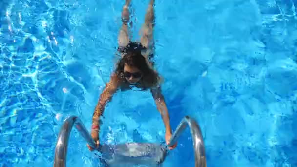 Mujer sexy nadando y saliendo de la piscina. Señora relajándose en el resort. Atractiva chica bronceada en traje de baño disfrutando de vacaciones de verano en el día soleado caliente refrescante en la cuenca del hotel. Cámara lenta Primer plano — Vídeo de stock