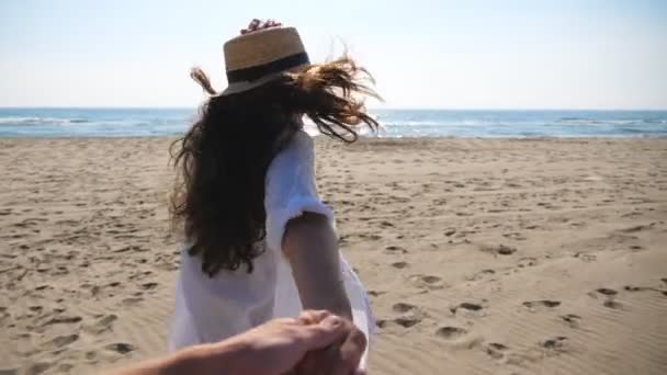 Girl holding male hand and running on tropical beach towards ocean. Follow me shot of woman leading her boyfriend on sea shore. Summer vacation concept. Scenic seascape at background. POV Slow mo — Stockvideo