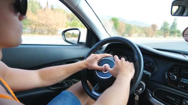 Unrecognizable man holding hands on steering wheel and driving car through country road at sunny summer day. Guy controlling his auto riding at highway on high speed. Concept of road trip. Slow motion — Stock Video