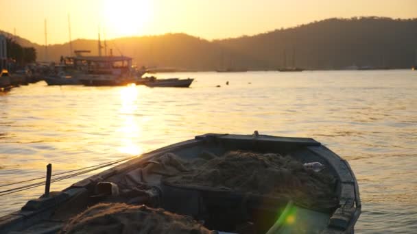 Bela vista na baía de barco de pesca balançando em ondas. Navios de pesca flutuando na superfície do mar com o pôr do sol no fundo. Luz solar dourada iluminando o ambiente oceânico. Capa marinha panorâmica — Vídeo de Stock