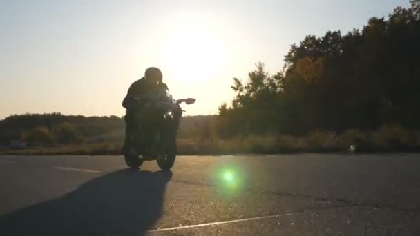 Muž v helmě jezdí rychle na moderní sportovní motorce na dálnici se sluneční erupcí na pozadí. Motorkář závodní jeho motocykl na venkovské silnici. Chlápek, co jezdí na kole. Pojem svoboda — Stock video