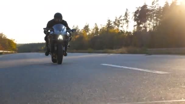 Vorderansicht eines jungen Mannes mit Helm, der auf einem modernen Sportmotorrad auf der Autobahn schnell unterwegs ist. Motorradfahrer rast mit seinem Motorrad auf Landstraße. Kerl fährt Fahrrad während der Fahrt. Konzept von Freiheit und Abenteuer — Stockvideo