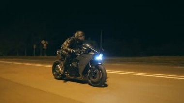 Miğferli genç adam şehir caddesinde modern siyah spor motosikletle hızlı gidiyor. Motosikletli, boş yolda motosikletiyle yarışıyor. Bisikletli adam. Özgürlük ve hobi kavramı. Kapat.