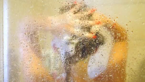 Blurred view on unrecognizable woman taking shower. Young girl standing in shower stall and enjoying drops of warm water. Beautiful lady caring for herself washing head. Slow motion Close up — Stockvideo