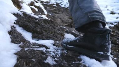 Tanınmayan yürüyüşçülerin ayakları seyahat sırasında tepeye tırmanır. Genç erkek turistlerin bacakları kaya yamacında yürüyor. Sağlıklı aktif yaşam tarzı. Kış tatili ya da tatil kavramı. Arka plan Yavaş çekim