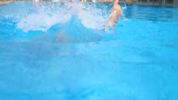 Jeune femme active plongeant dans la piscine et éclaboussant l'eau. Dame relaxant sur station tropicale. Femme en maillot de bain sautant dans le bassin avec de l'eau fraîche et rafraîchissante lors d'une journée ensoleillée. Concept vacances d'été. Gros plan — Video