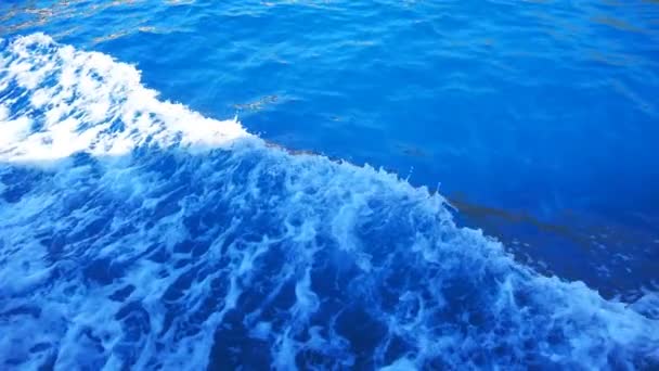 Vista dal lato della barca a motore nuoto e spruzzi di acqua di mare limpida. Barca a vela galleggiante e facendo traccia sulla superficie dell'oceano. Concetto di viaggio o vacanza in località tropicale. Rallentatore Close up — Video Stock