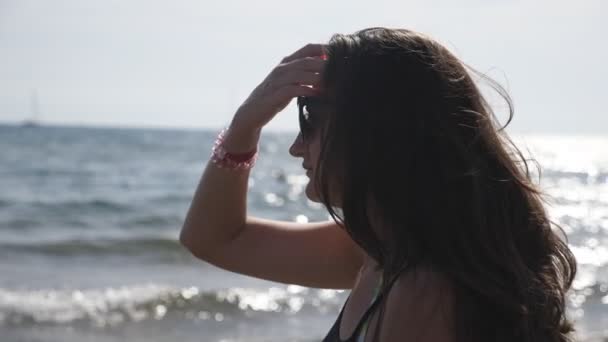 Perfil de mujer viajera caminando por la costa del océano admirando hermosas vistas. Mujer morena disfrutando de un momento idílico tranquilo en la orilla del mar y su viaje de verano en el resort. Paisaje marino escénico de fondo — Vídeos de Stock