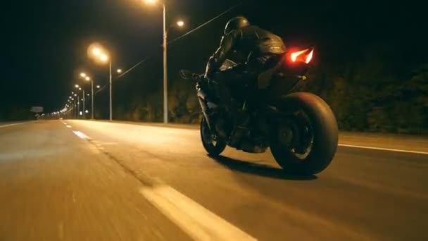 Człowiek jadący szybko na nowoczesnym motocyklu sportowym na nocnej ulicy miasta. Motocyklista ściga się na pustej drodze. Facet jeżdżący na rowerze o zmierzchu. Pojęcie wolności i przygody. Niski kąt widzenia zbliżenie — Wideo stockowe