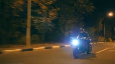 Motosikletli, gece yolunda motosikletiyle yarışıyor. Akşam sokağında farları açık bir şekilde modern spor motosikletle sürat yapan genç bir adam. Alacakaranlıkta bisiklet süren adam. Özgürlük kavramı. Ön görünüm Kapat