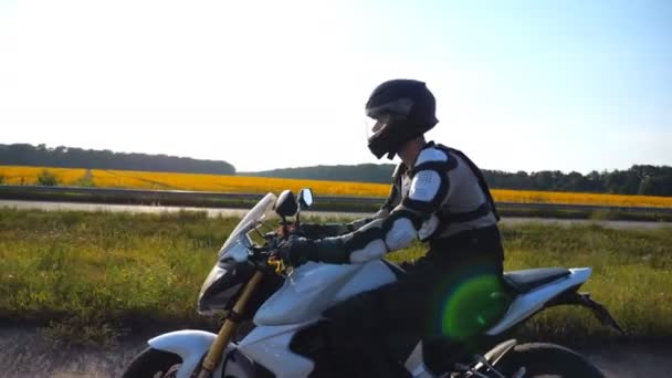 Man in helmet riding fast on sport motorbike along highway with scenic view at background. Motorcyclist speeding on motorcycle through country road. Guy enjoying speed. Freedom concept. Side view — 图库视频影像