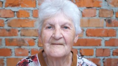 Genç adam ve yetişkin kadın sevgili büyükannelerini yanaklarından öpüyor. Gülümseyen ve kameraya bakan mutlu büyükannenin portresi. Sıcak aile ilişkileri. Sevgi ya da ilgi kavramı. Yavaş çekim