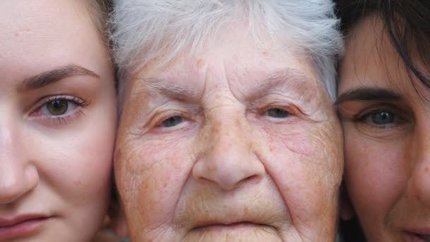 Retrato de mulher idosa com sua filha e neta olhando para a câmera juntos. Três caras femininas. Lento movimento Fechar — Vídeo de Stock