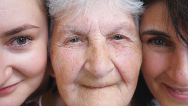 Retrato de mulher idosa com sua filha e neta olhando para a câmera e sorrindo juntos. Senhoras felizes mostrando emoções alegres nos rostos. Expressão facial positiva das mulheres. Fechar — Vídeo de Stock