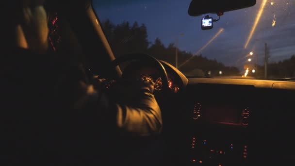 Le conducteur masculin tient la main sur le volant et roule en auto sur l'autoroute la nuit. Il conduit une voiture moderne le soir. Jeune homme se déplace dans sa voiture SUV sur la route vide. Gros plan Mouvement lent — Video