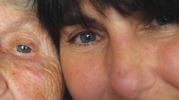 Τα μάτια της ηλικιωμένης γυναίκας και της ενήλικης κόρης της κοιτάζουν μαζί στην κάμερα. Γέρος και νέος. Προβολή λεπτομερειών Αργή κίνηση Κοντινό πλάνο — Αρχείο Βίντεο