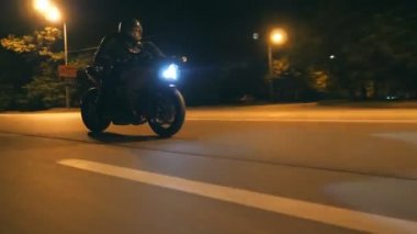 Miğferli genç adam şehir caddesinde modern siyah spor motosikletle hızlı gidiyor. Motosikletli, boş yolda motosikletiyle yarışıyor. Bisikletli adam. Özgürlük ve hobi kavramı. Kapat.