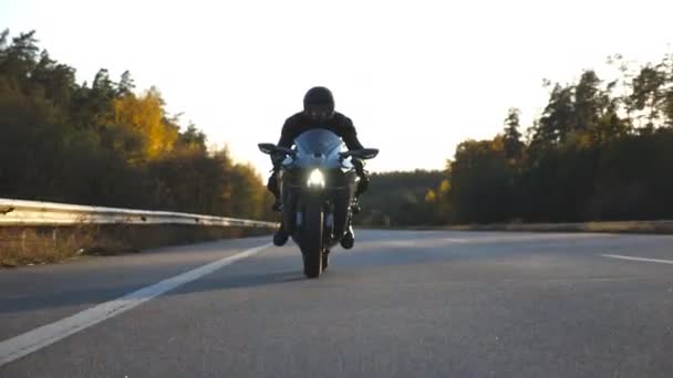 Motorcyclist racing his motorcycle on country road. Young man in helmet riding fast on modern sport motorbike at highway. Guy driving bike during trip. Concept of adventure. Front view Close up — Stock Video