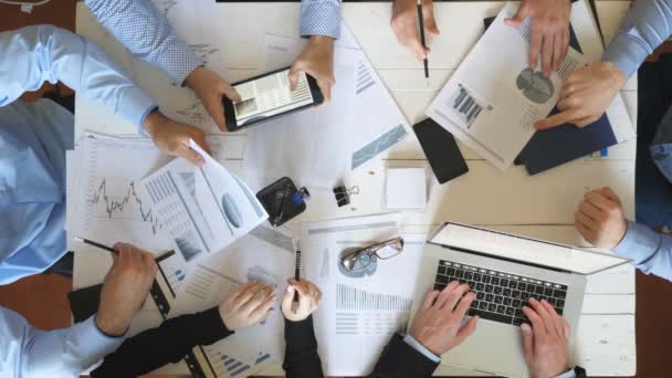 Top view manos de hombres y mujeres de negocios planificación de la estrategia para el proyecto corporativo en la oficina. Equipo de negocios sentado en la mesa y revisando gráficos financieros. Colaboradores examinando documentos en el escritorio — Vídeos de Stock