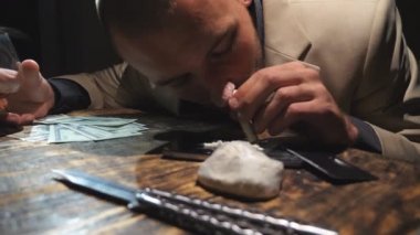 Uyuşturucu koklayan genç bir uyuşturucu satıcısının telefon ekranından 100 dolarlık banknot çekmesi. Kokain aşırı dozundan bayılan bir erkek. Bağımlılık ve madde bağımlılığı kavramı