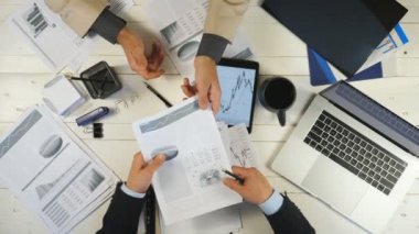 Grafikleri kontrol eden ve ofiste mali raporları tartışan iki genç iş adamının üst düzey erkek eli. Başarılı iş arkadaşları masada oturuyor ve yeni bir iş projesi geliştiriyor.