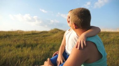 Neşeli baba ve gülümseyen çocuk birlikte vakit geçirip doğayla eğleniyorlar. Küçük oğluyla çimlerin üzerinde oturan ve onu işaret eden mutlu bir baba. Yavaş çekim