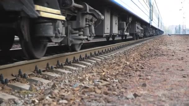 Cierre de ruedas de acero giratorias del tren que se mueve a lo largo de la vía férrea. Transporte ferroviario de pasajeros pasando por una cámara. Concepto de transporte y viajes. Vista de ángulo bajo Cámara lenta — Vídeo de stock