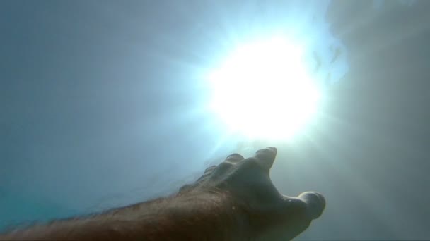 Bras demandant de l'aide et essayant d'atteindre le soleil. Point de vue de l'homme se noyant dans la mer ou l'océan et flottant à la surface. La main masculine s'étend de sous l'eau aux rayons du soleil. Mouvement lent POV — Video