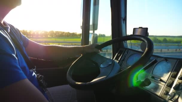 Unrecognizable man sitting behind wheel of his truck and riding through countryside at sunset. Close up steering wheel and dashboard of truck. Beautiful landscape at background. Slow motion Side view — Stock Video