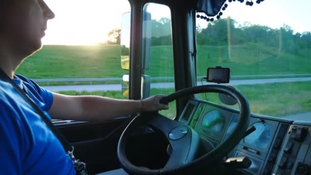 Lorry driver riding through countryside at sunset time. Man controlling his truck driving to destination. Close up steering wheel and dashboard of car. View inside lorry cab. Side view Slow motion — Stock Video